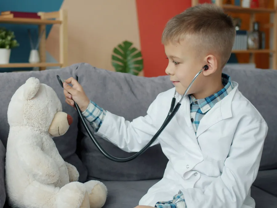 Ein Kind hört einen Teddybären mit dem Stethoskop ab